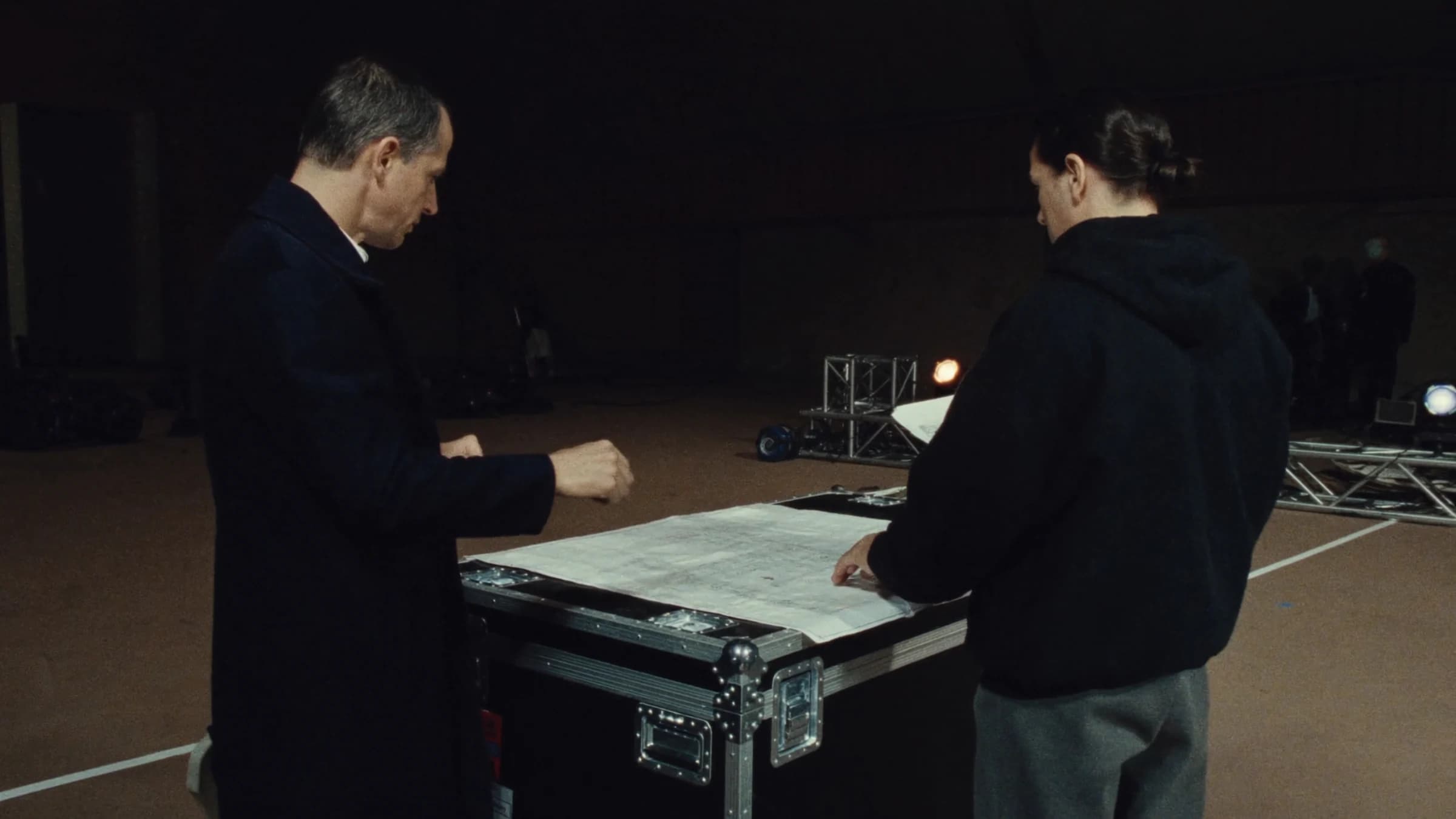 Un cliente y un técnico repasan el plano del escenario sobre un flight case.